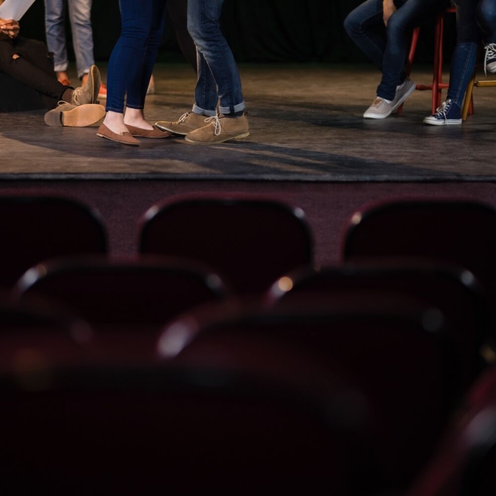 skådespelare står på scenen och övar, bara deras fötter syns