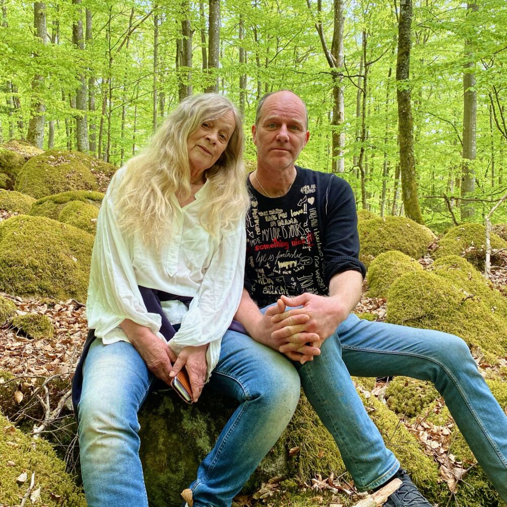 Ett par - en kvinna och en man - sitter på stenen i skogen