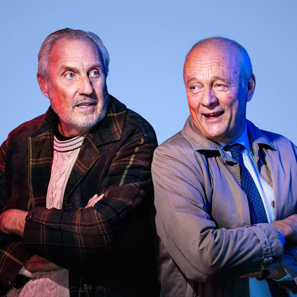 två äldre män sitter med ryggen mot varandra