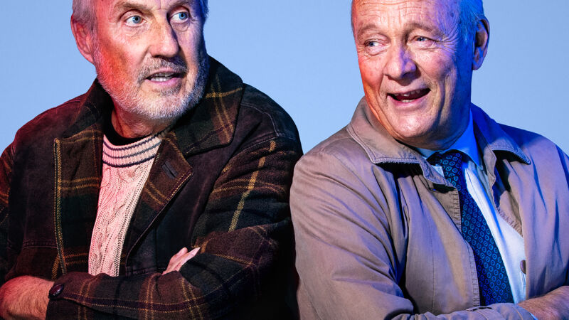 två äldre män sitter med ryggen mot varandra