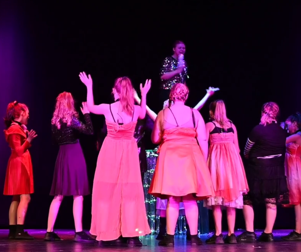 ungdomar står på scenen i rosa kläder