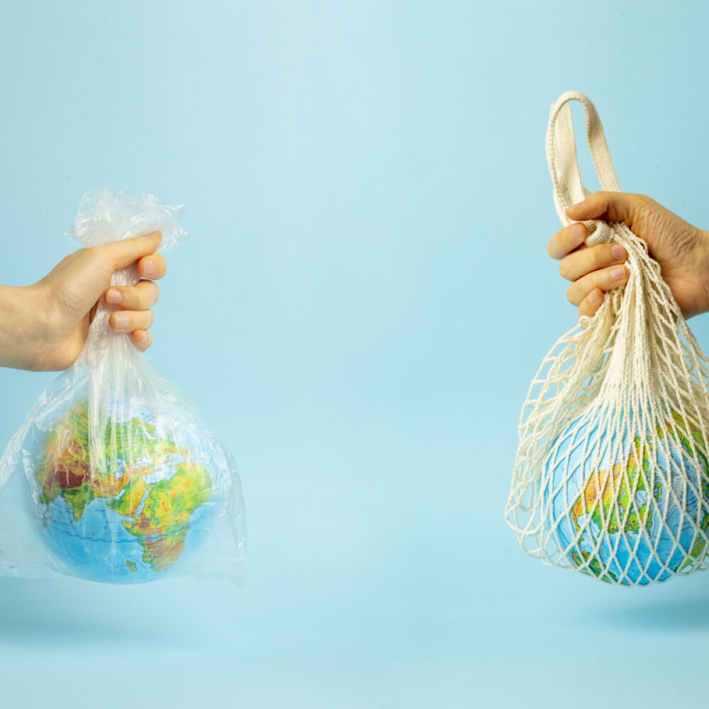 Två händer håller jorden och en jord är omplastat, den andra i tygpåse