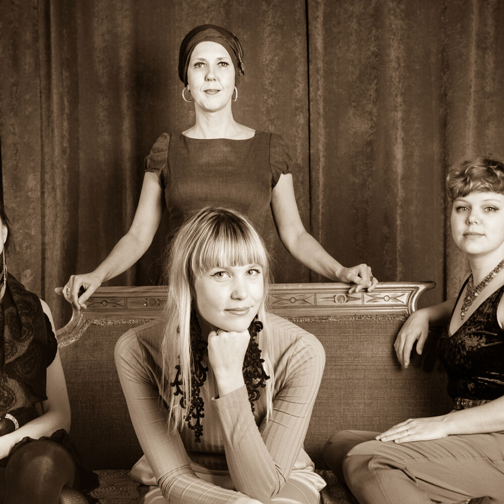 tre kvinnor: en stor bakom soffa, tre sitter