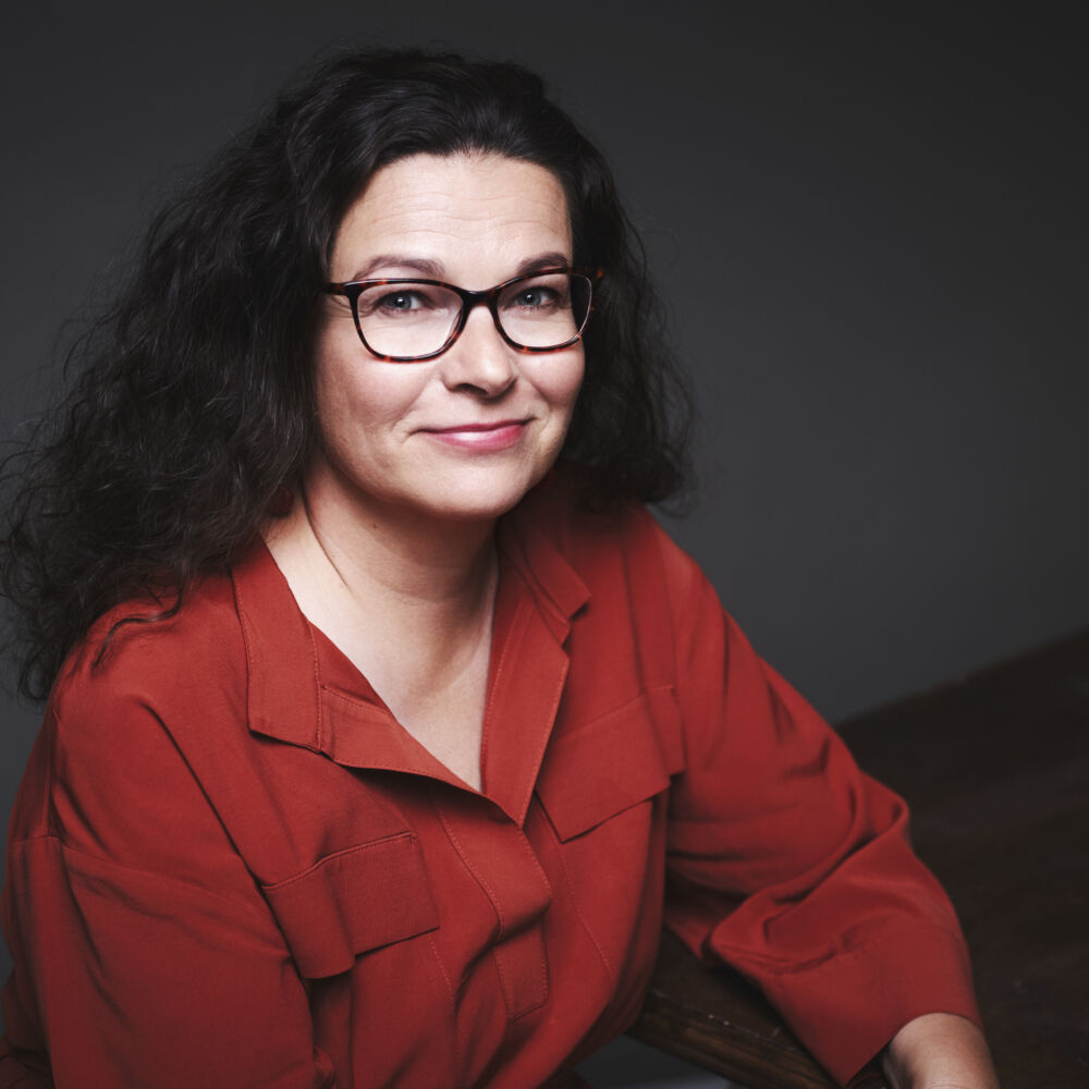en kvinna i glasögon, med mörka hår och i en röd skjorta