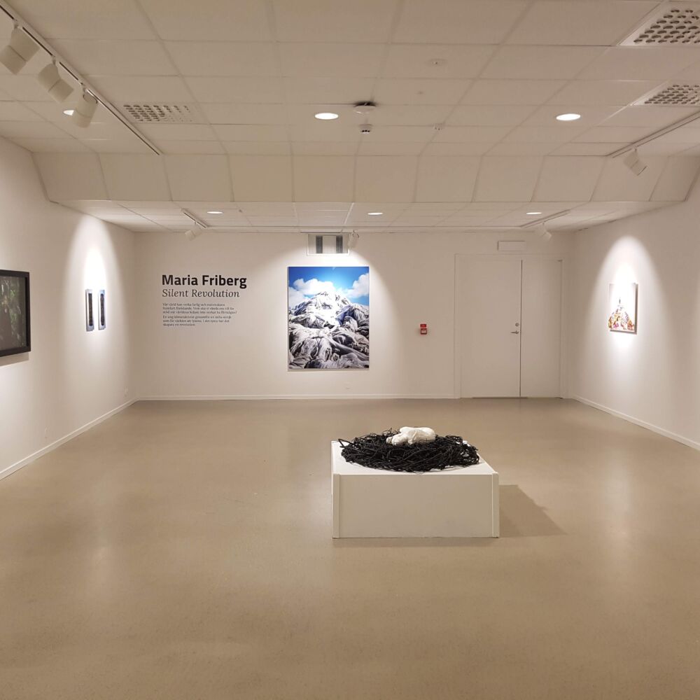 Konsthallens vita rum med fotografier på väggarna och en skulptur i mitten