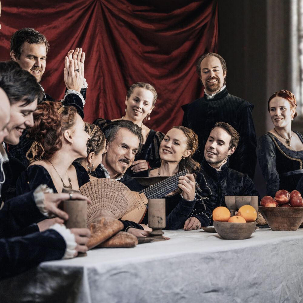 en grupp människor i gamla kostymer sitter vid bordet