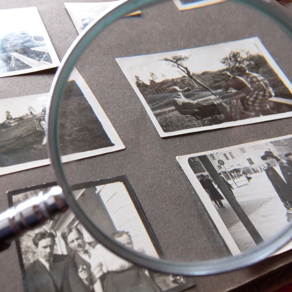 Tittar genom förstoringsglaset på gamla bilder i fotoalbum.