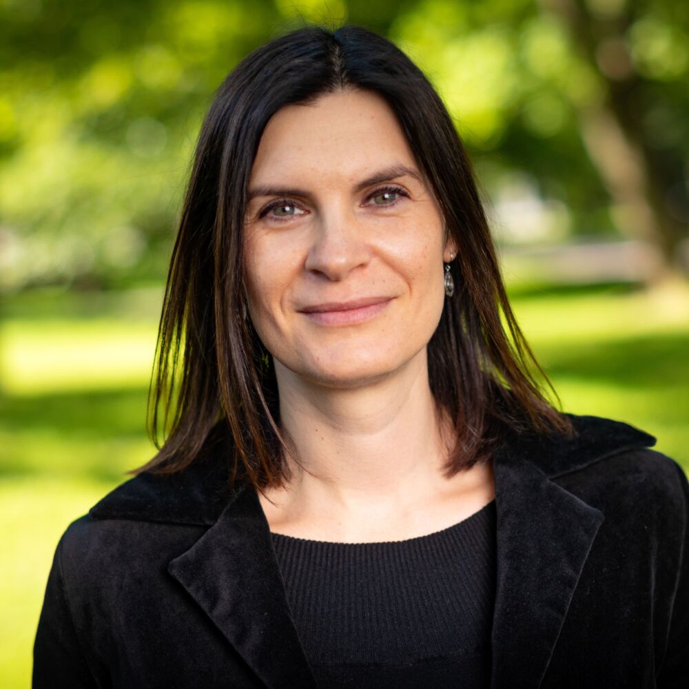 en kvinna med brun hår och i en svart tröja i parken