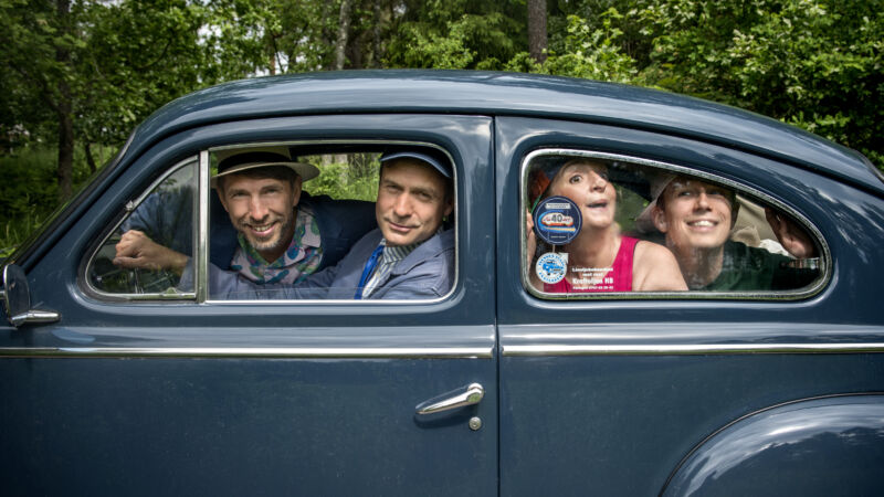en kvinna och tre män sitter i en blå bil