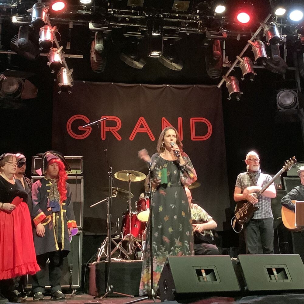 en musikgrupp står på scenen, bakom de syns ett namn Grand