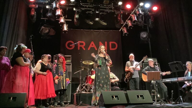 en musikgrupp står på scenen, bakom de syns ett namn Grand