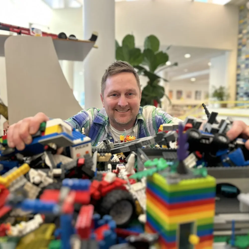 Man som sitter med massa lego framför sig.