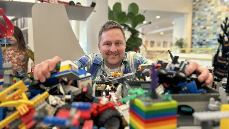 Man som sitter med massa lego framför sig.