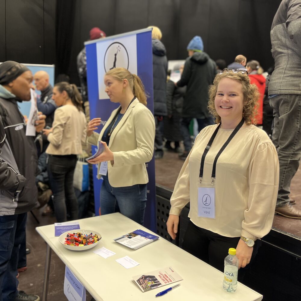 Människor som står vid bord på en mässa.