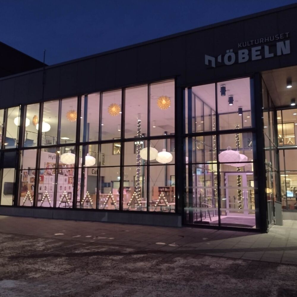 Glasad fasad på ett kulturhus med rosa belysning inuti