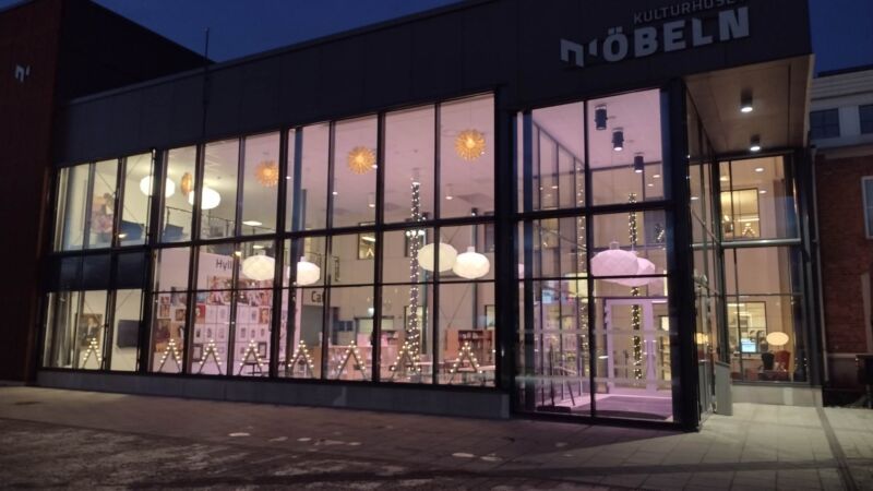 Glasad fasad på ett kulturhus med rosa belysning inuti