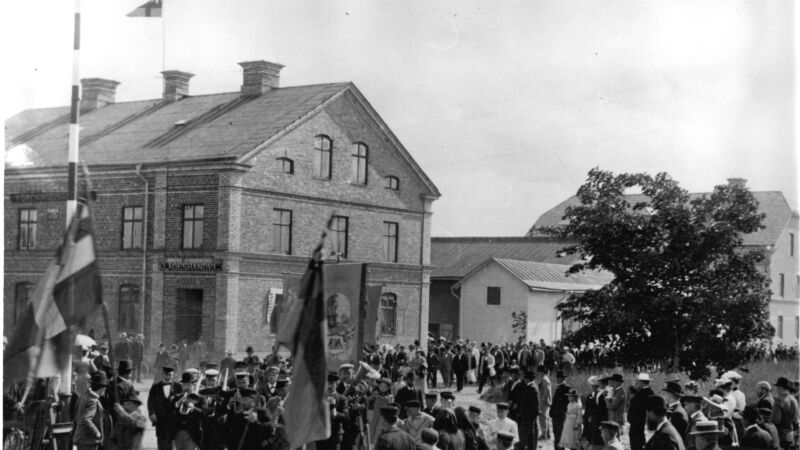 Svart-vit bild av ett hus och människor i Tierp från början av 1900-talet