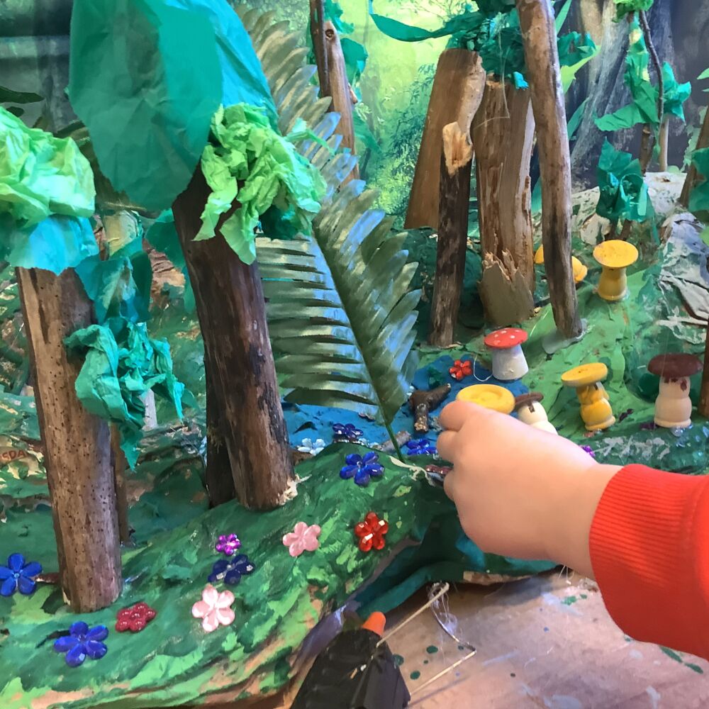 skogslandskap i glada färger och en barnhand