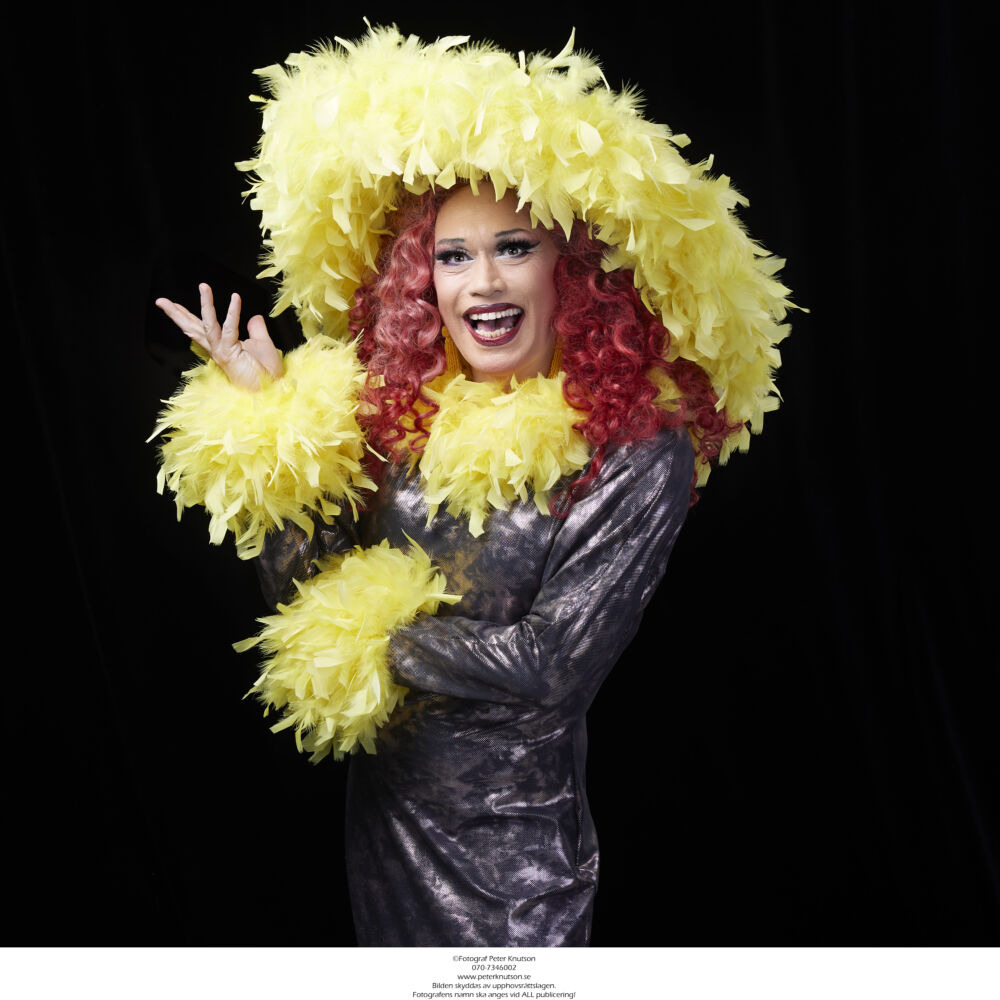 en skådespelare kläd ut sig i fina kvinnliga kläder med glitter