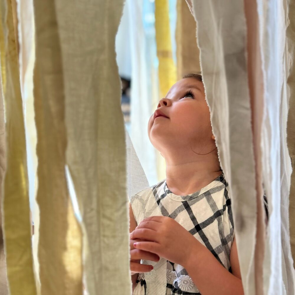 en liten flicka bland hängande tyg i konsthallen