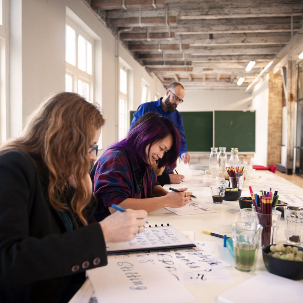 två kvinnor och en man sitter vid ett bord och textar