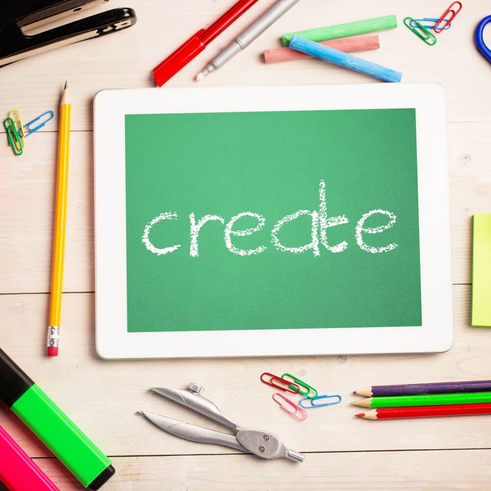 Pennor och sax och ge på ett bord. I mitten står det Create