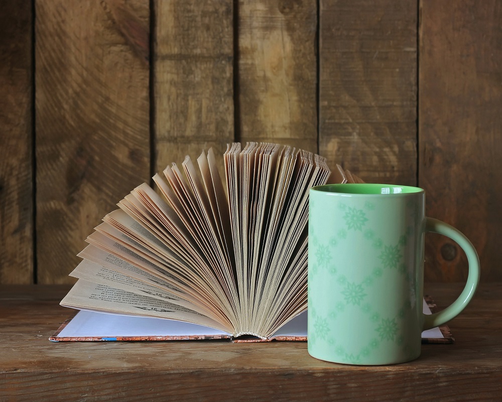 Bild på turkos kaffemugg och en uppslagen bok