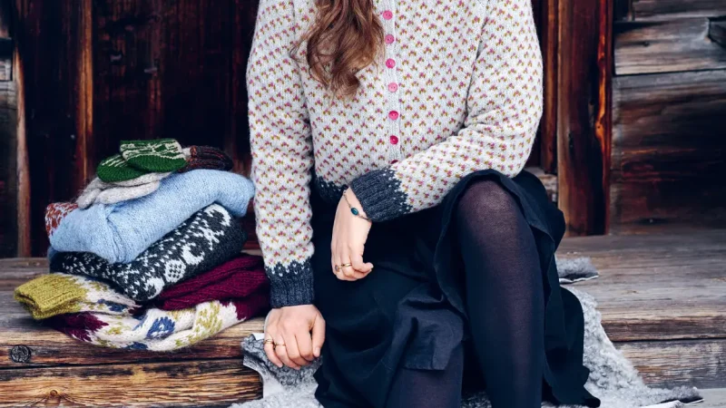 Maja Karlsson, författare sitter på en trätrappa med beige kofta, kjol och långt hår.