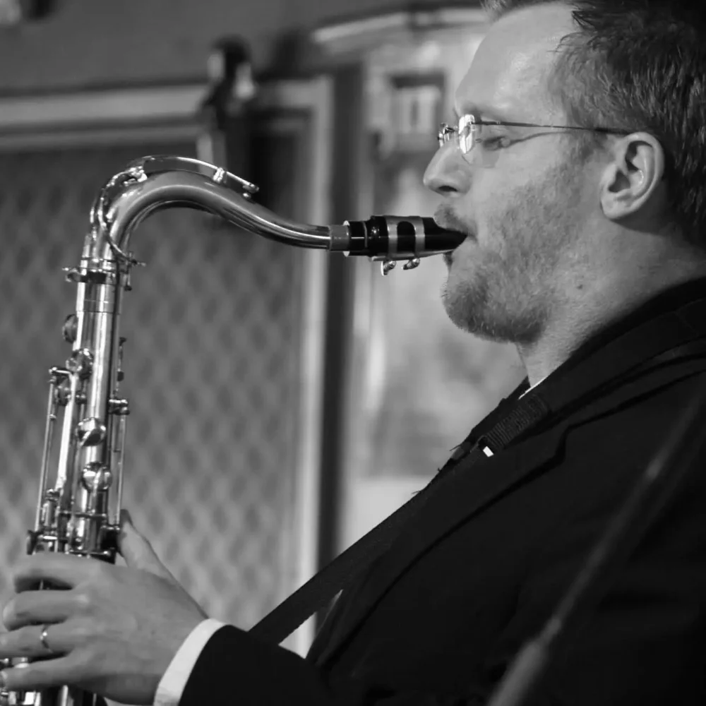 Svart vit bild på en man som blåser i en saxofon