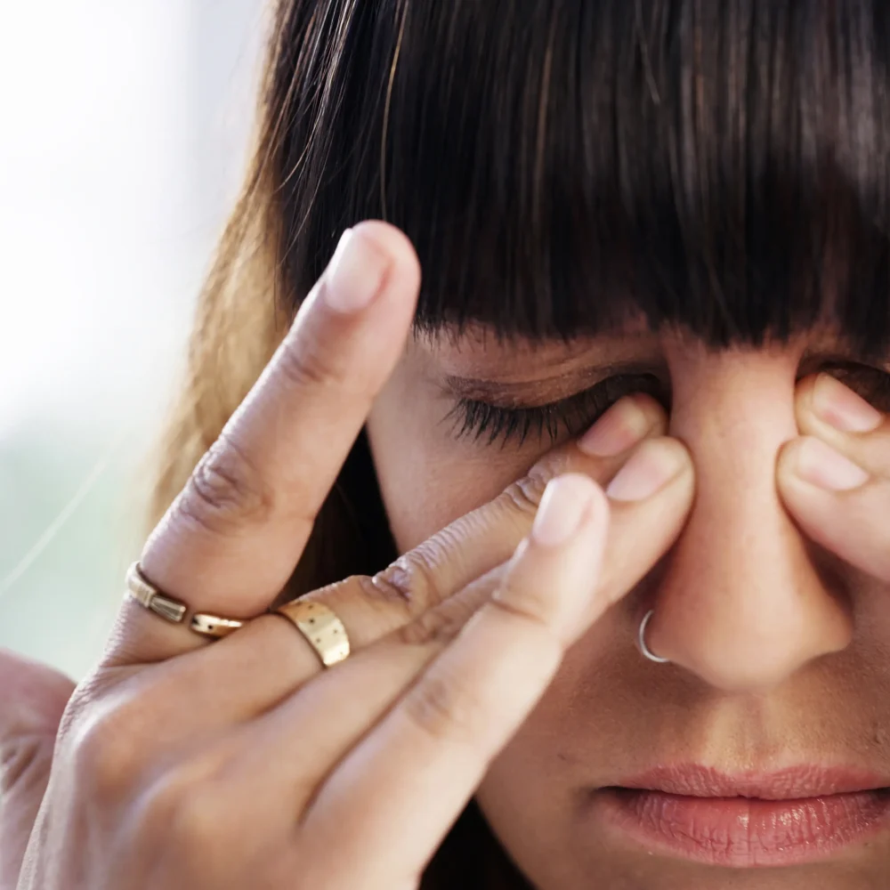 Kvinna som håller fingrarna mot ögonen som om hon har huvudvärk
