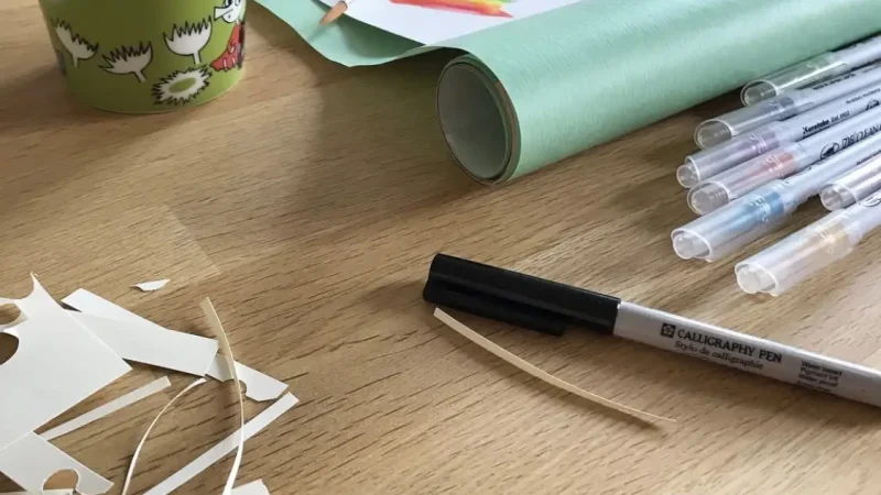 papperspyssel, penna och papper på ett bord