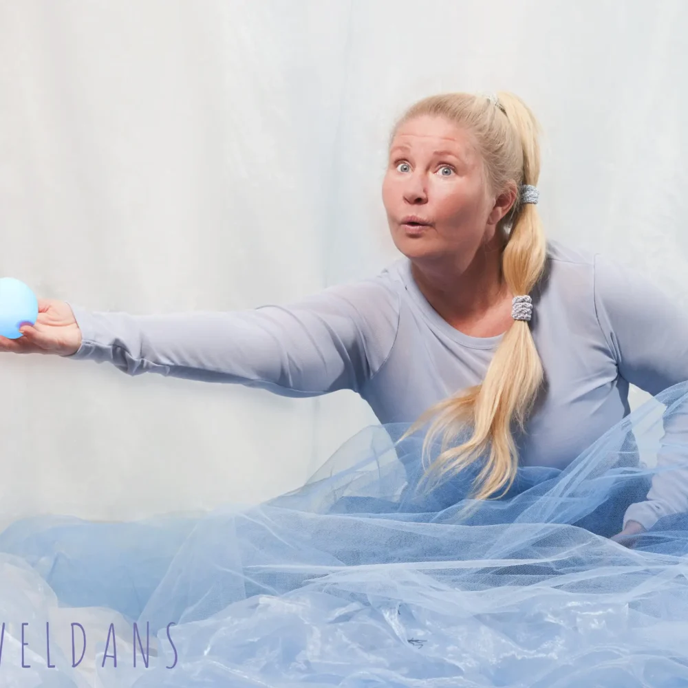 Kvinna i blå kläder håller ut en blå boll i handen.