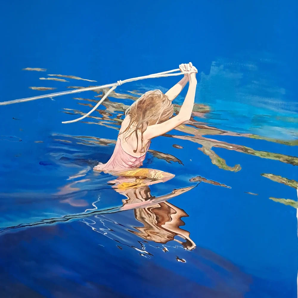 en flicka i baddräkt går genom blått vatten och drar i ett snöre som hon håller över huvudet