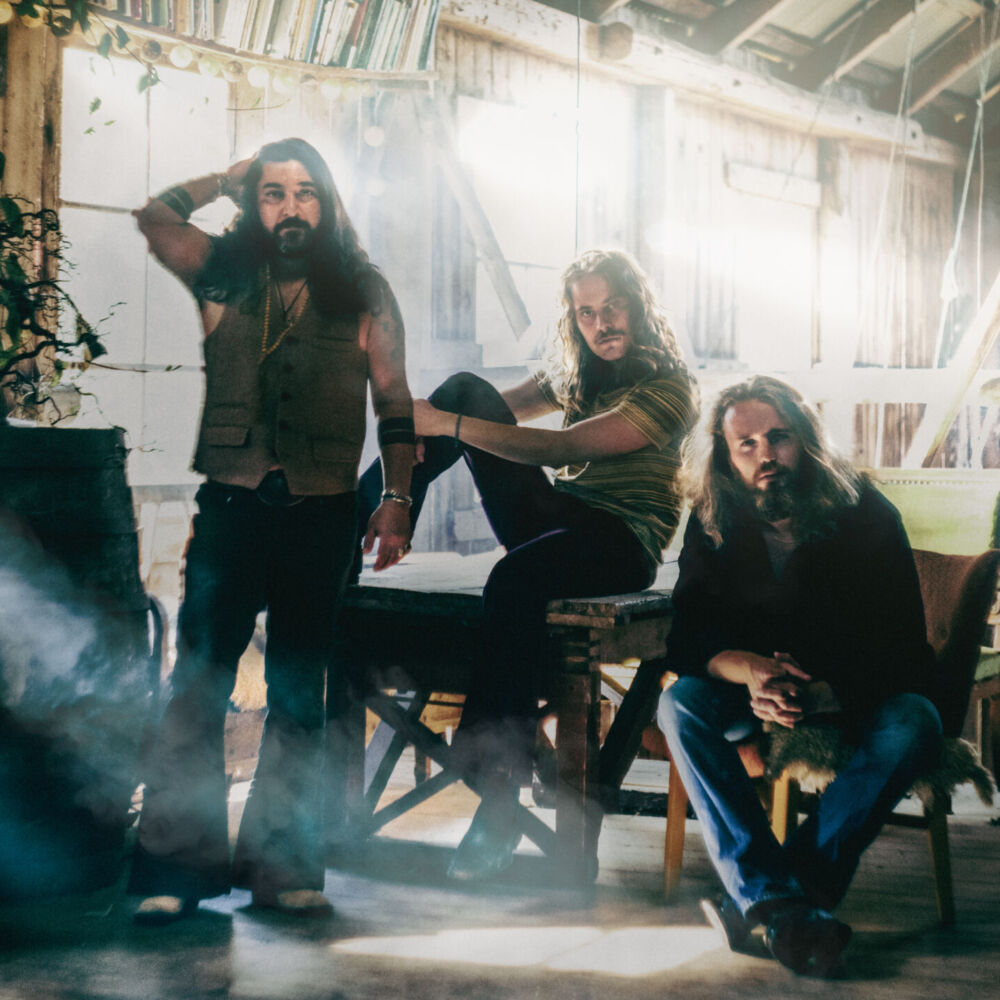 Tre bandmedlemmar som står i en lada.