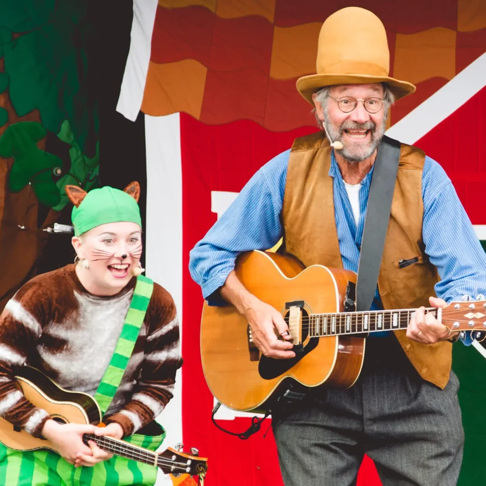 Kvinna util lkatt och en man utklädd till gubbe i hatt. De kallas Pettsson och findus