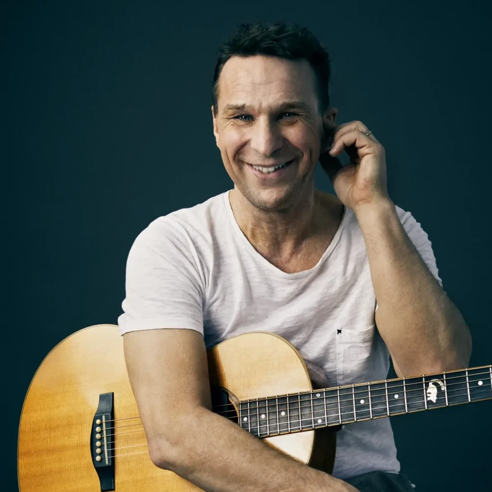 anders lundin, en man som sitter på en pall med en guitar och i jeans och vit t-shirt