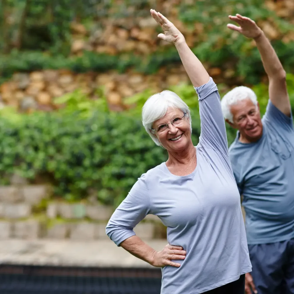 två äldre personer tränar yoga i naturen