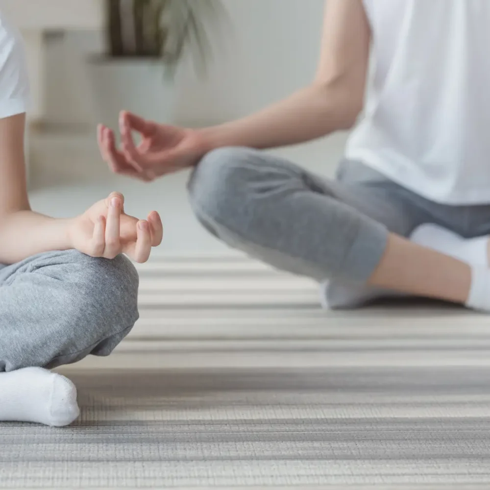 Beskuren bild av mor och dotter som mediterar i lotusställning tillsammans